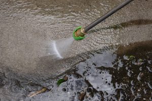 Closeup photo of a concrete surface being power washed