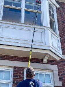 Photo of Greg using an extension pole to clean upper story windows