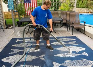 Photo of a blue rug with fish patterns being hot steamed cleaned by a worker in a blue shirt